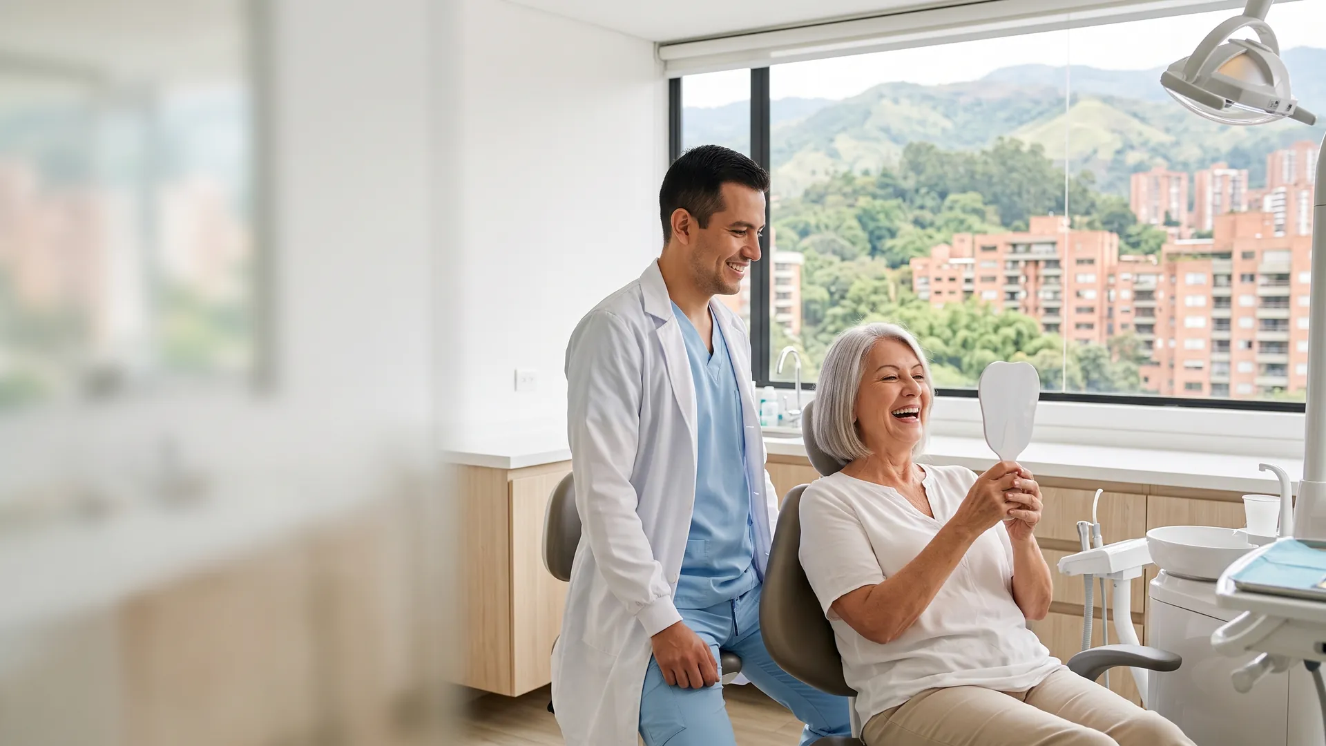 A woman in her seventies laughs as she checks her smile in a hand mirror while her dentist in Medellín looks on